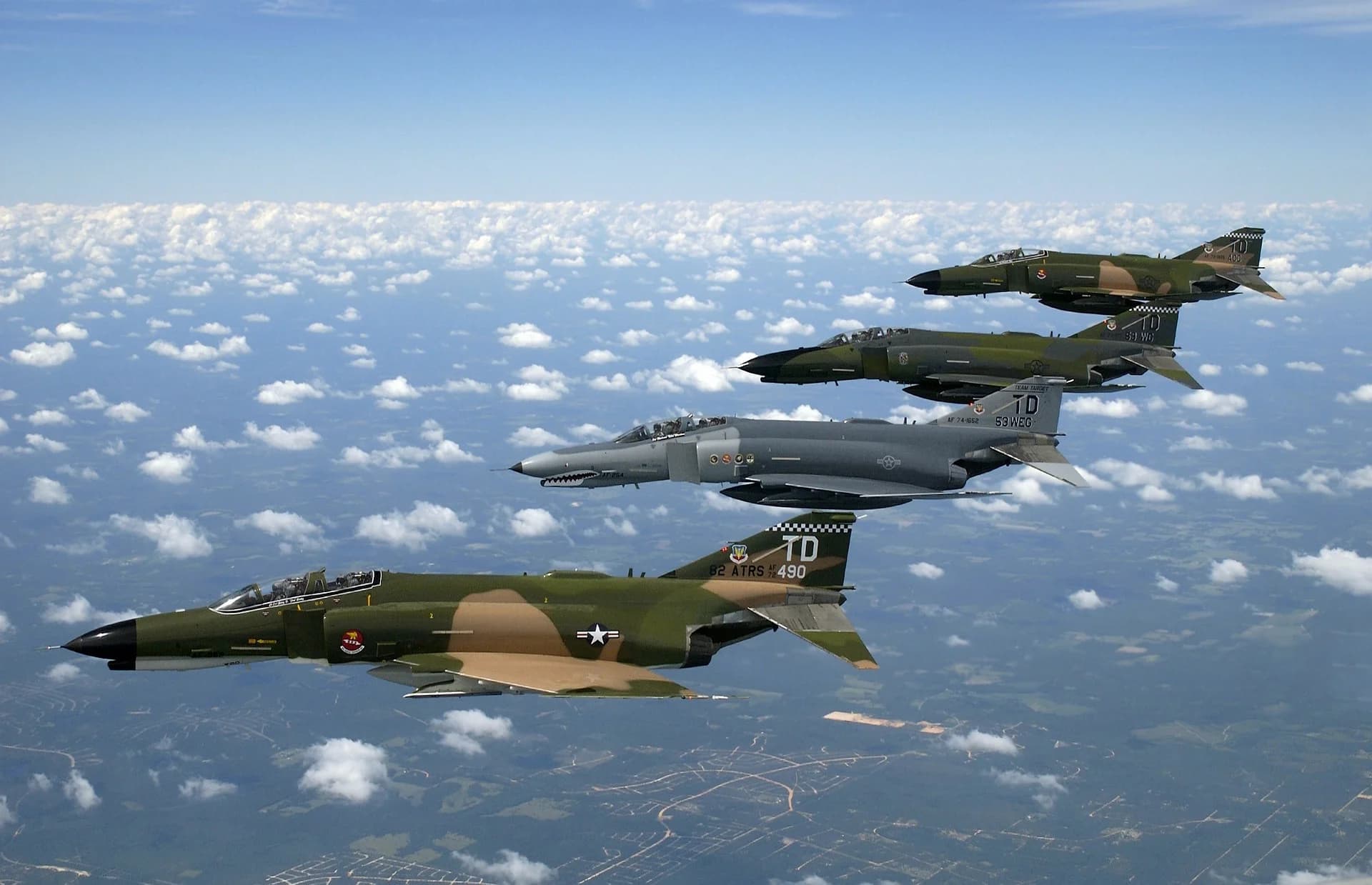 F-4E Phantom II aircraft flying in formation above clouds